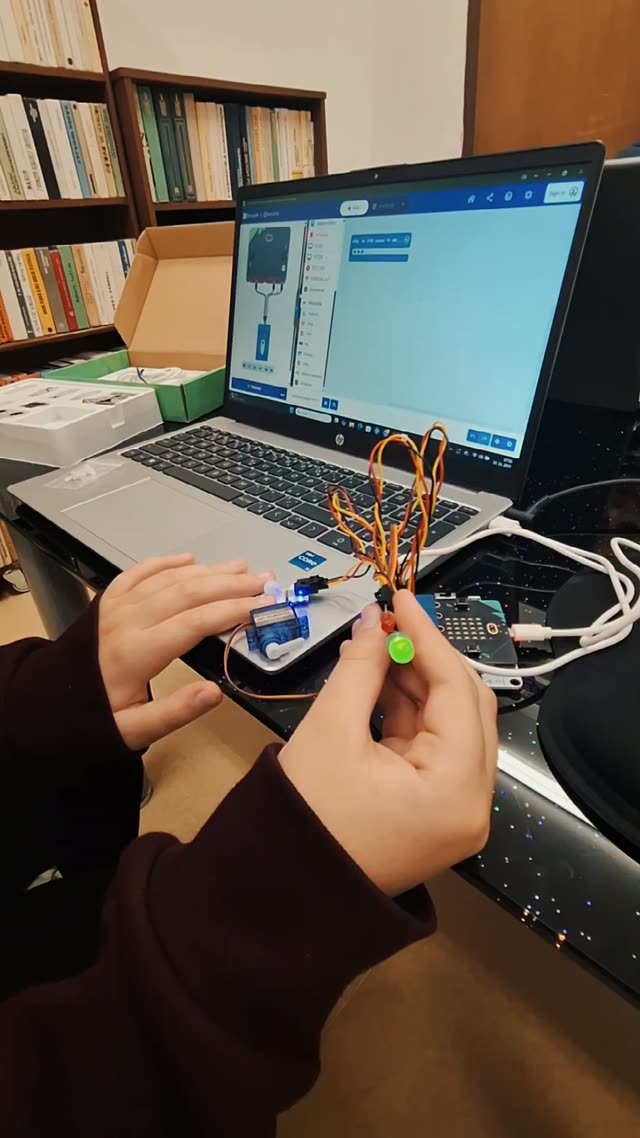 Ruky dieťaťa zapájajú servo a LED diódy k micro:bitu, prvý krok k projektu, ktorý sa hýbe a svieti