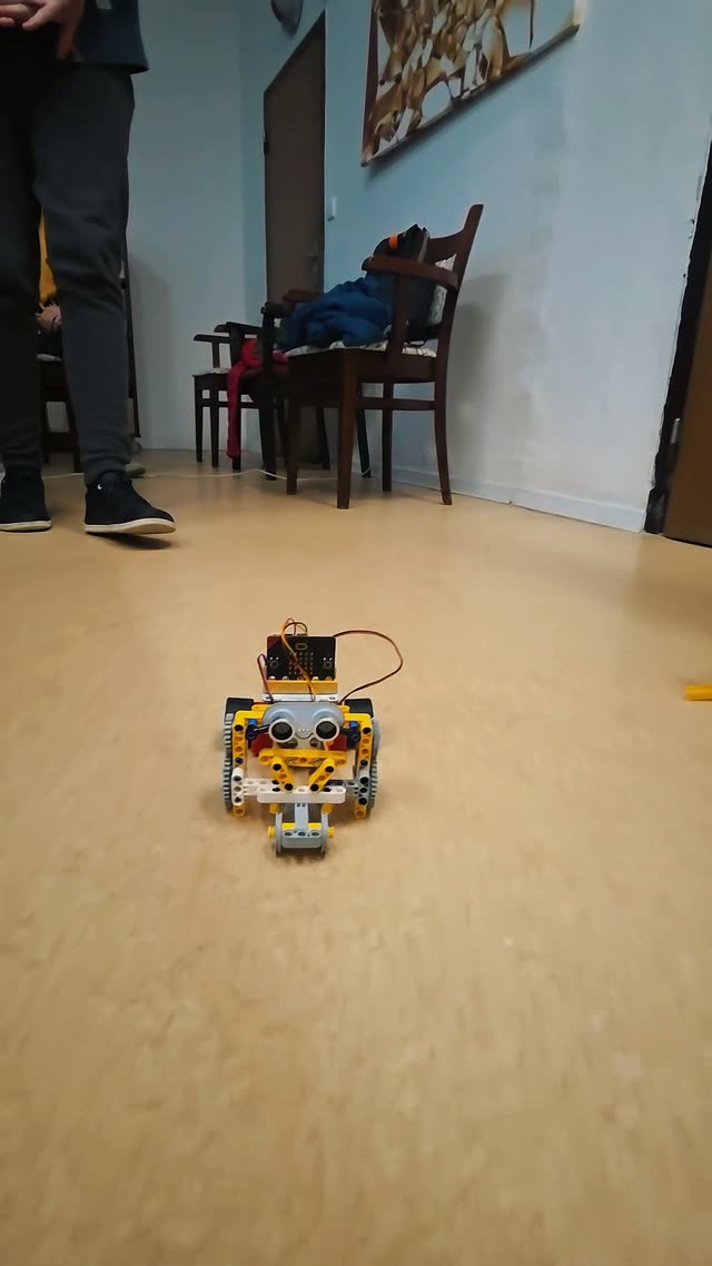 Lego autíčka s micro:bitom jazdia po podlahe so zapnutými svetlami podľa programu, ktorý do nich deti nahrali