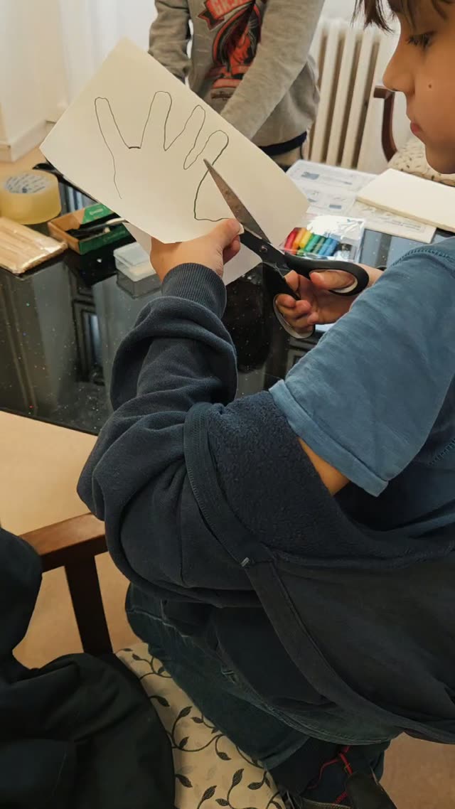 Dieťa vystrihuje papierovú dlaň pre projekt mávajúcej ruky, projekty na krúžku sa nielen programujú, ale aj reálne vyrábajú