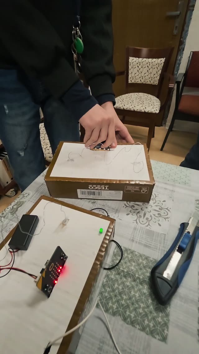 Dieťa nasadzuje micro:bit do konštrukcie arkádovej hry Pevná ruka, ktorú si samo postavilo