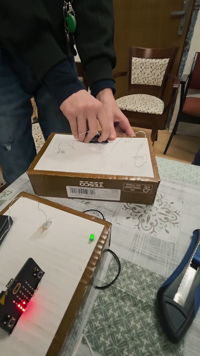 Dieťa stavia konštrukciu pre arkádovú hru Pevná ruka, ktorú potom pripojí na micro:bit