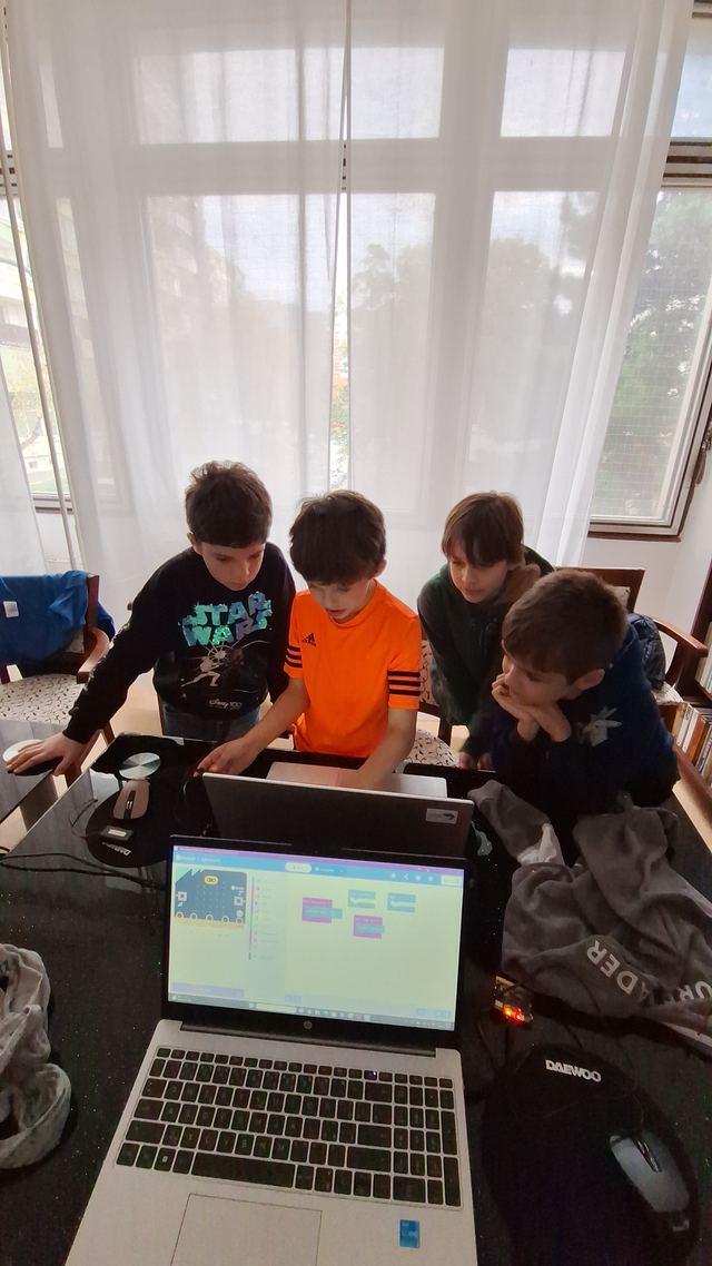 Deti sa spoločne skláňajú nad notebookom a hľadajú chybu v programe poskladanom v MakeCode