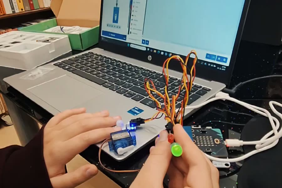 Dieťa zapája servo, LED diódy a micro:bit k notebooku na krúžku