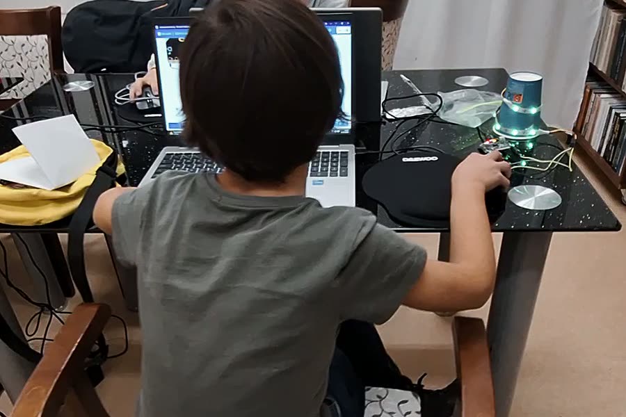 Deti programujú Mikulášsky maják v zatemnenej miestnosti, projekty im svietia na stole